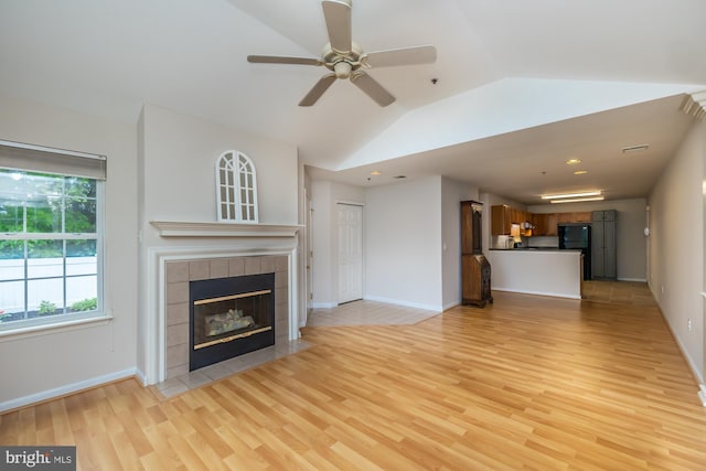 unfurnished living room with light wood finished floors, lofted ceiling, a fireplace, a ceiling fan, and baseboards
