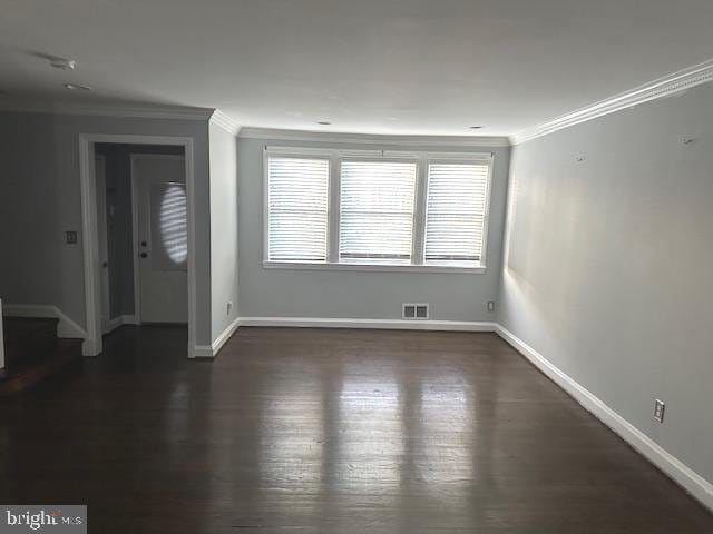 unfurnished room featuring crown molding, baseboards, dark wood-style floors, and stairs