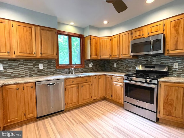 8408 Alvin Rd, Pasadena, MD 21122 - kitchen featuring stainless steel appliances, a sink, ceiling fan, brown cabinetry, and tasteful backsplash