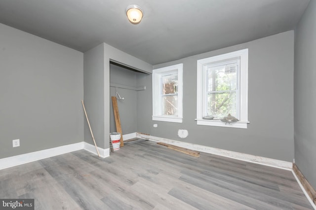 unfurnished bedroom featuring wood finished floors, baseboards, and a closet