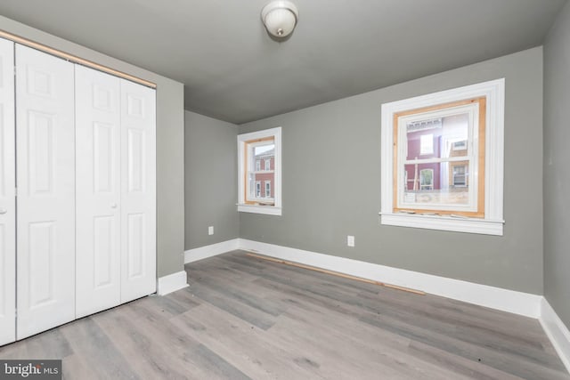 unfurnished bedroom with baseboards, a closet, and wood finished floors