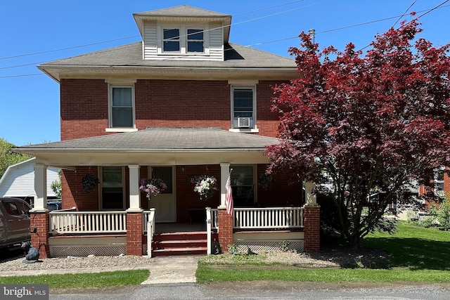 traditional style home with covered porch, brick siding, and a shingled roof