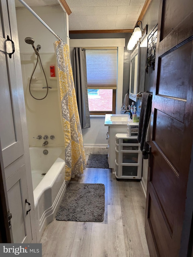 bathroom with wood finished floors, shower / bath combo with shower curtain, vanity, baseboards, and ornamental molding