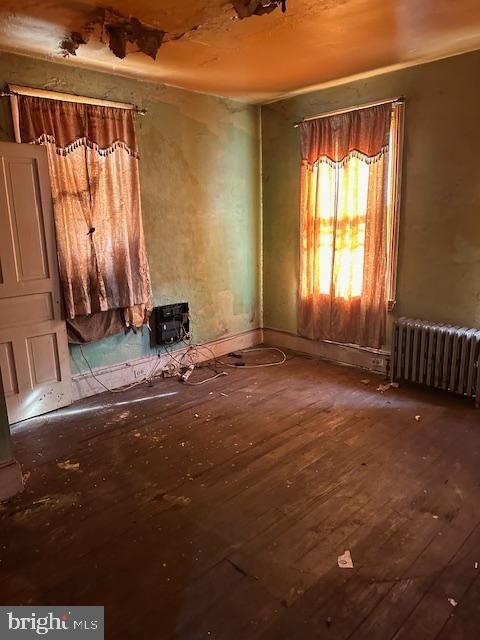 spare room with radiator heating unit and wood-type flooring