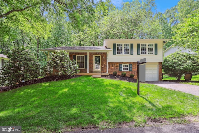 split level home with driveway, brick siding, a garage, and a front lawn