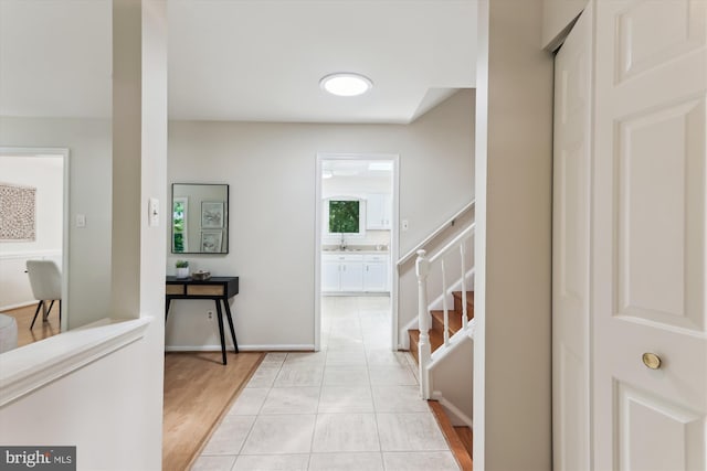 hall featuring a sink, stairs, and light wood-style floors