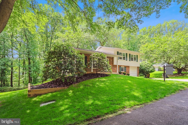 split level home with brick siding, driveway, a front yard, and a garage
