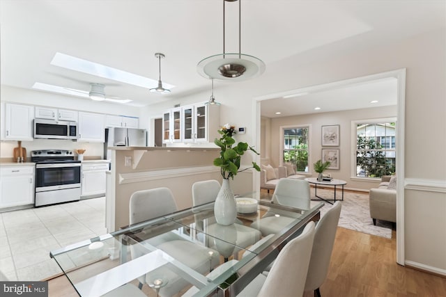 dining space featuring a skylight and light wood-type flooring