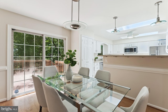dining space with light wood-type flooring, baseboards, and ceiling fan