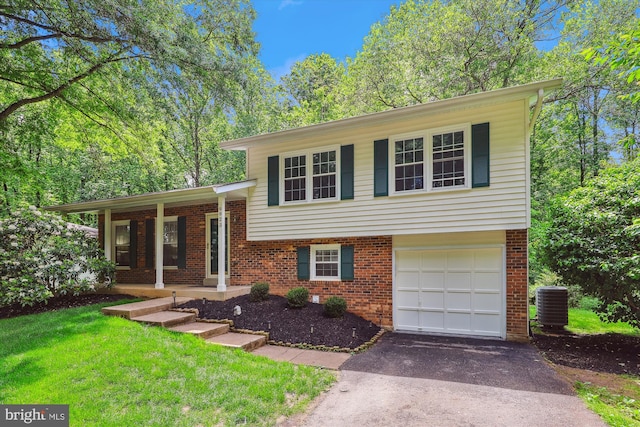 tri-level home featuring asphalt driveway, cooling unit, brick siding, and an attached garage