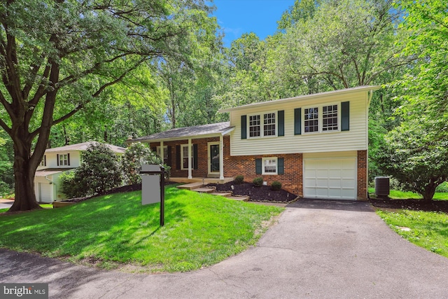tri-level home featuring brick siding, asphalt driveway, central AC, a front lawn, and a garage