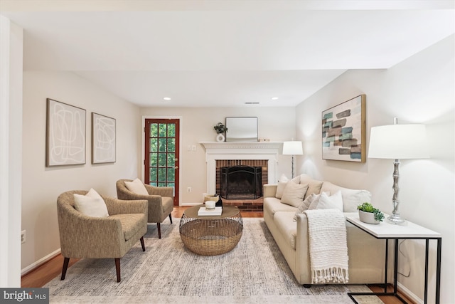 living room featuring wood finished floors, a brick fireplace, recessed lighting, and baseboards
