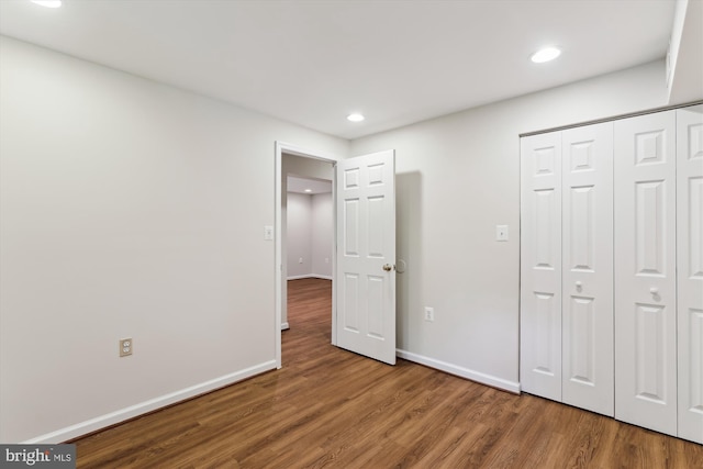 unfurnished bedroom with wood finished floors, recessed lighting, baseboards, and a closet