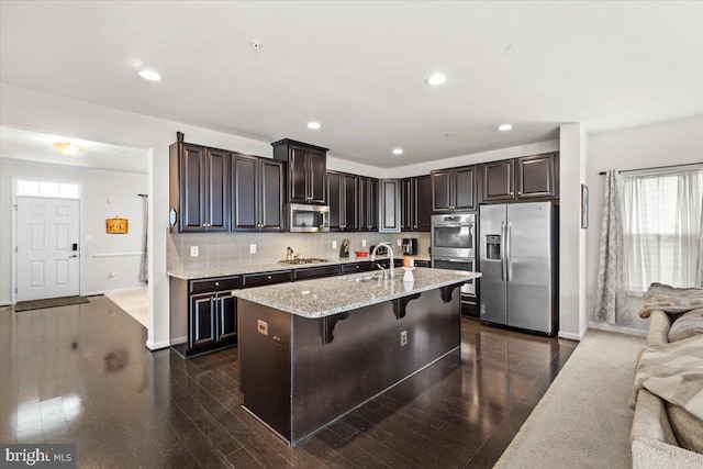 2121 River Heritage Blvd, Dumfries, VA 22026 - kitchen featuring stainless steel appliances, a kitchen bar, decorative backsplash, a sink, and light stone counters