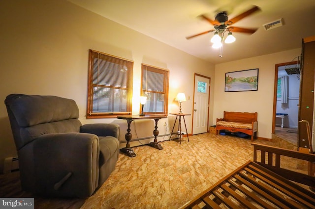 living area with a baseboard heating unit, a ceiling fan, and baseboards