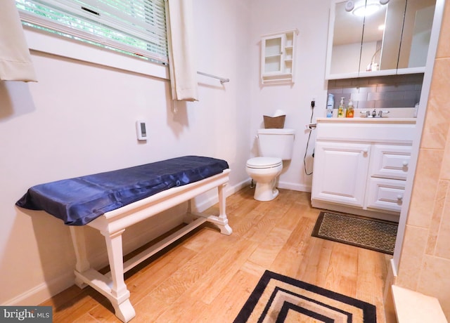 bathroom with wood finished floors, toilet, backsplash, baseboards, and vanity