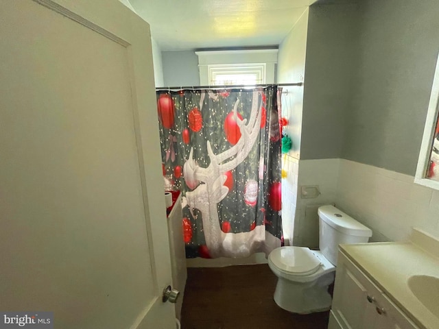 bathroom featuring a wainscoted wall, toilet, tile walls, and vanity