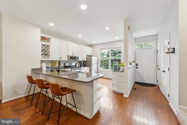 517 Bullock Unit 13, Conshohocken, PA 19428 - kitchen with open shelves, appliances with stainless steel finishes, dark stone countertops, a sink, and a peninsula