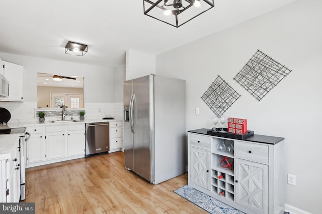 835 Sabina Cir, Bear, DE 19701 - kitchen with stainless steel appliances, a sink, light wood-style flooring, white cabinetry, and backsplash