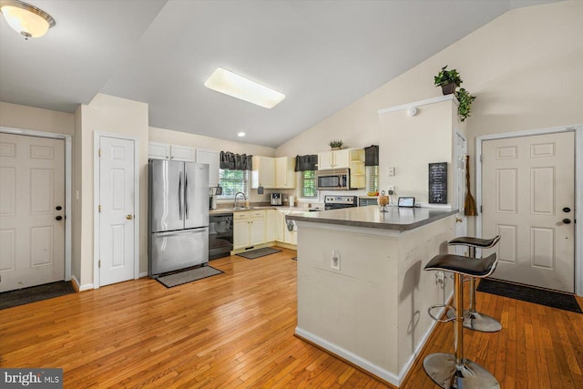 309 6th St, Colonial Beach, VA 22443 - kitchen with stainless steel appliances, lofted ceiling, a sink, a peninsula, and light wood-type flooring