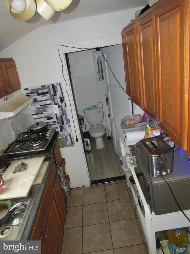 kitchen with tile patterned floors, gas cooktop, extractor fan, and brown cabinetry