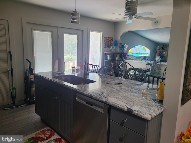 kitchen featuring stainless steel dishwasher, a ceiling fan, dark wood-style floors, light stone counters, and pendant lighting