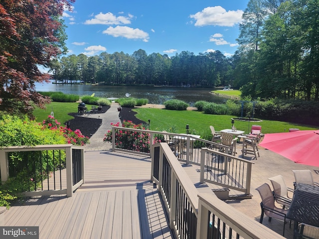 wooden terrace with a water view, a lawn, outdoor dining area, and a patio