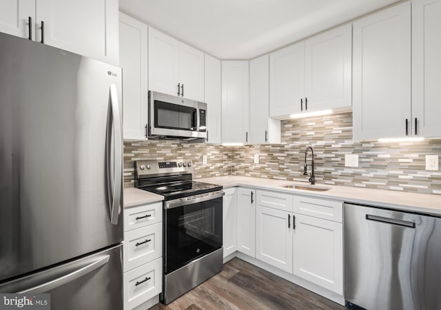 kitchen with stainless steel appliances, a sink, light countertops, dark wood finished floors, and white cabinets