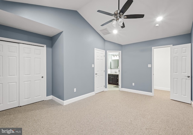 unfurnished bedroom featuring light carpet, lofted ceiling, baseboards, a closet, and connected bathroom