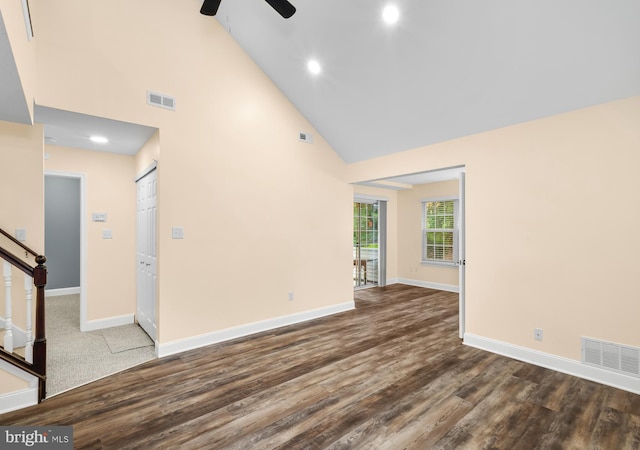 unfurnished living room with high vaulted ceiling, ceiling fan, baseboards, wood finished floors, and stairway