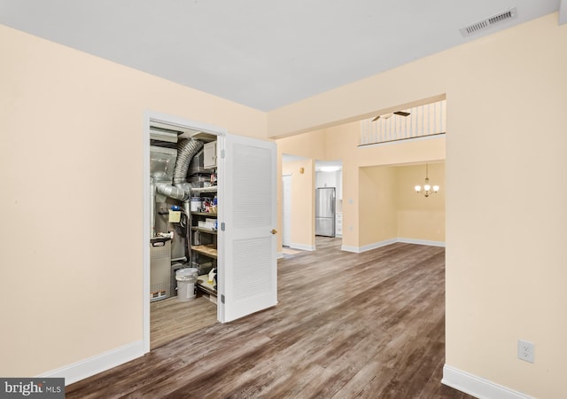 spare room with wood finished floors, baseboards, and a chandelier