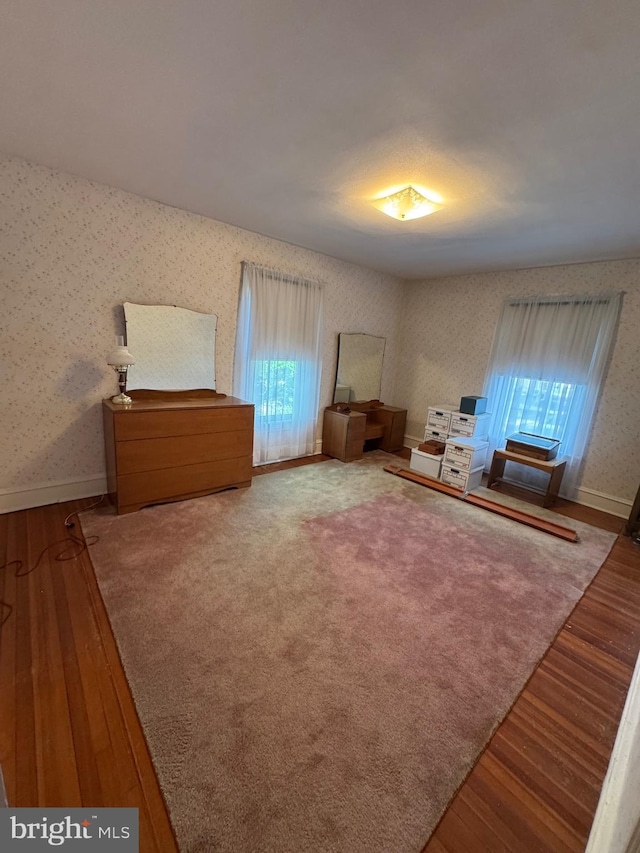 sitting room featuring wood finished floors, wallpapered walls, and baseboards