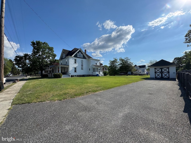 view of side of home with a yard, a storage shed, and an outbuilding