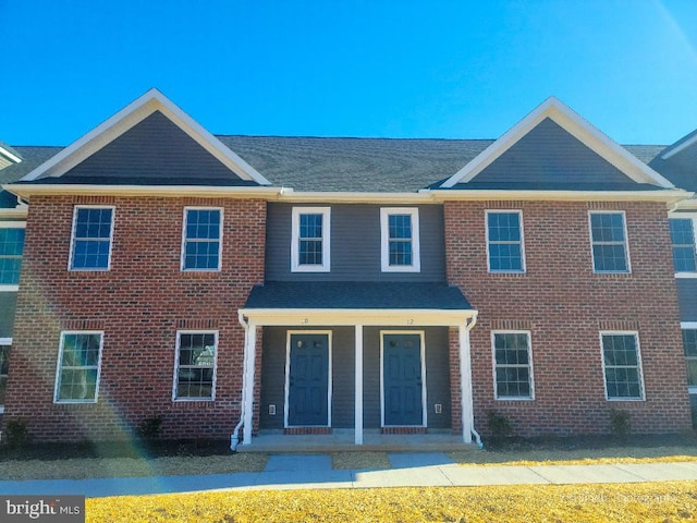 townhome / multi-family property with a porch and brick siding