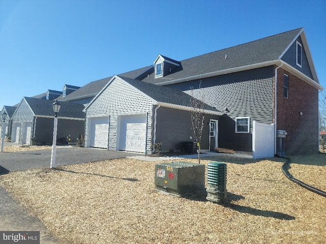 view of side of property with an attached garage, asphalt driveway, and brick siding