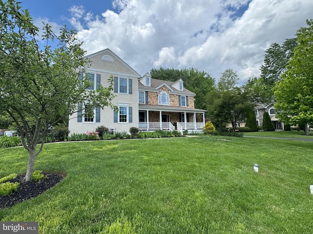 view of front of home featuring covered porch, a front lawn, and stone siding