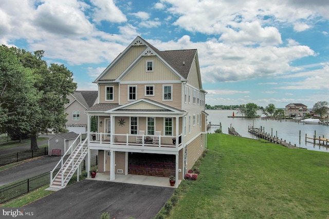 view of front of house with a water view, board and batten siding, driveway, a front lawn, and a garage