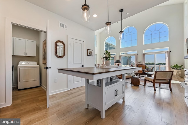 kitchen featuring washer / dryer, white cabinetry, light wood-type flooring, dark countertops, and recessed lighting