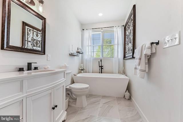 full bath with baseboards, a freestanding tub, toilet, vanity, and marble look tiles