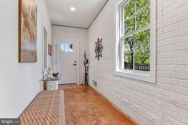 doorway to outside with concrete floors and brick wall
