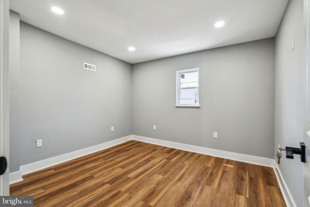 spare room with wood finished floors, baseboards, and recessed lighting