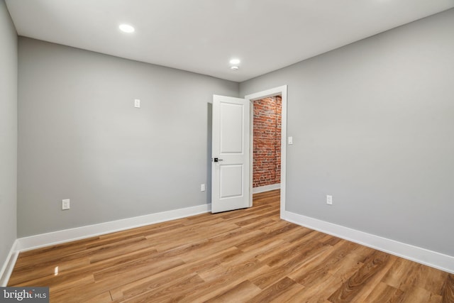 spare room with baseboards, light wood-style floors, and recessed lighting