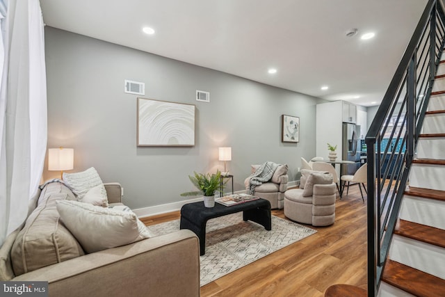 living area with stairs, light wood-style flooring, recessed lighting, and baseboards
