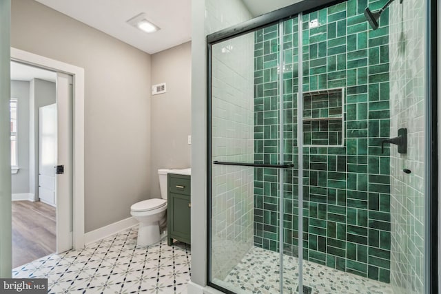 full bath featuring a stall shower, vanity, tile patterned floors, baseboards, and toilet
