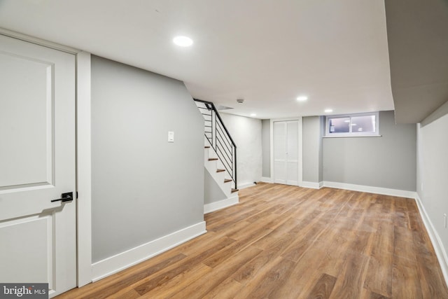 below grade area featuring recessed lighting, wood finished floors, baseboards, and stairs
