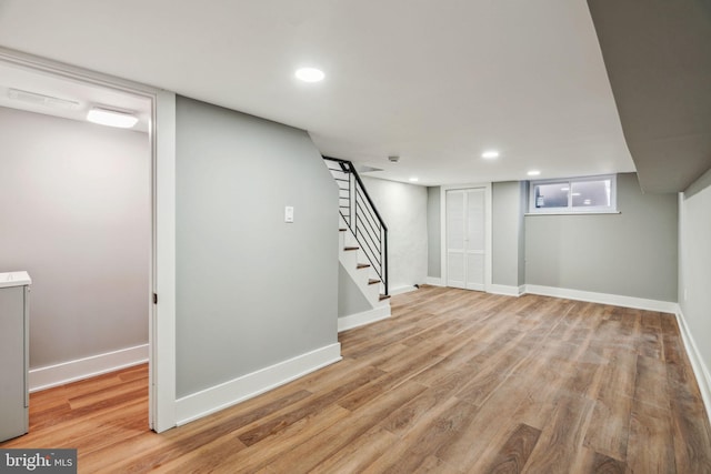 basement featuring recessed lighting, light wood-style floors, stairs, and baseboards