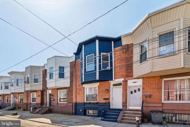 townhome / multi-family property featuring entry steps, brick siding, and a residential view