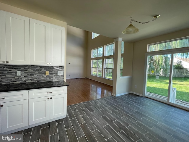 kitchen with baseboards, plenty of natural light, tasteful backsplash, and white cabinetry