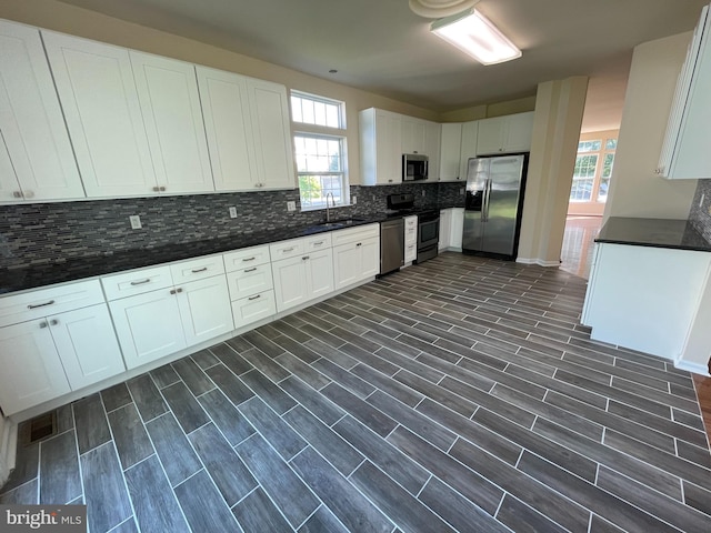 kitchen featuring stainless steel appliances, dark countertops, backsplash, and healthy amount of natural light