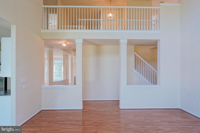 unfurnished living room featuring wood finished floors, baseboards, and a high ceiling
